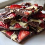 A stack of rich Chocolate Covered Strawberry Bark pieces featuring dark chocolate, white chocolate swirls, and fresh strawberry slices.