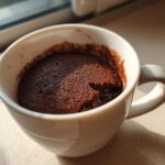 Close-up of a freshly baked Chocolate Lava Mug Cake inside a white mug, showing the rich, dark top.
