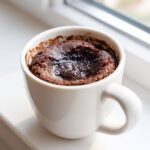 Close-up of a warm Chocolate Lava Mug Cake with a molten center in a white ceramic mug.