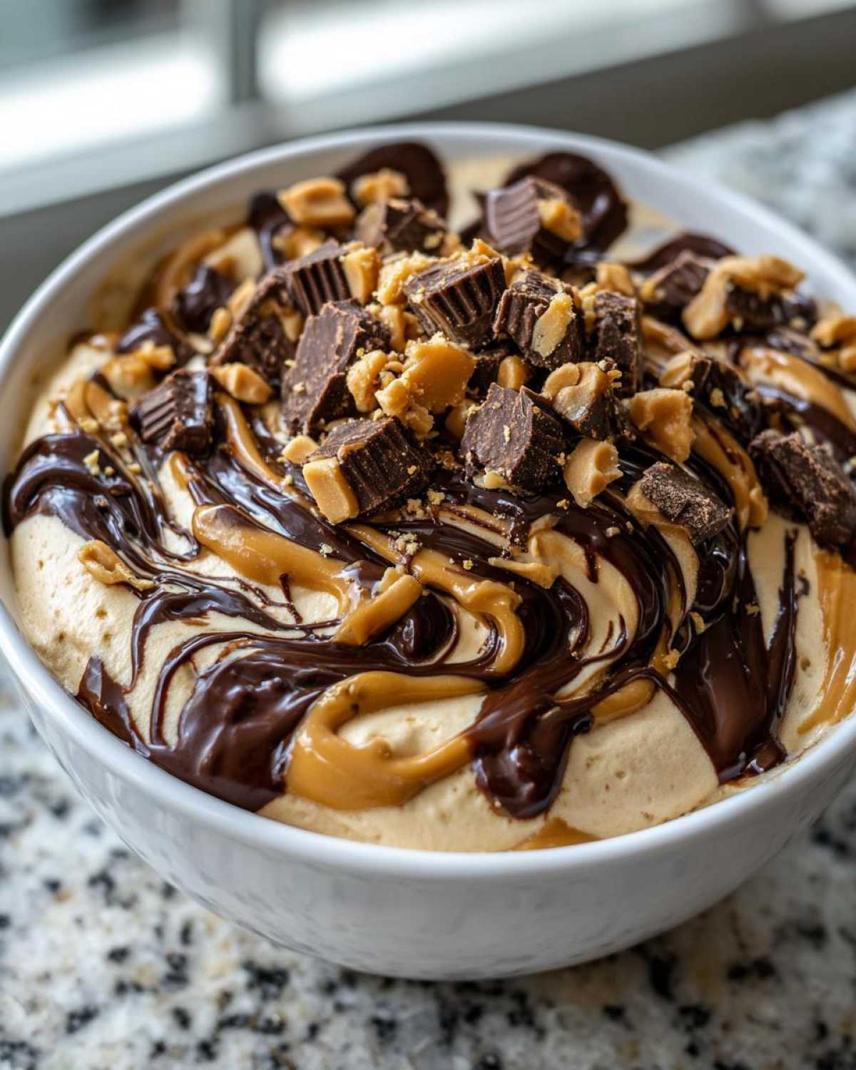 Close-up of a creamy Chocolate Peanut Butter Cheesecake Dip swirled with chocolate and peanut butter, topped with chopped peanut butter cups.