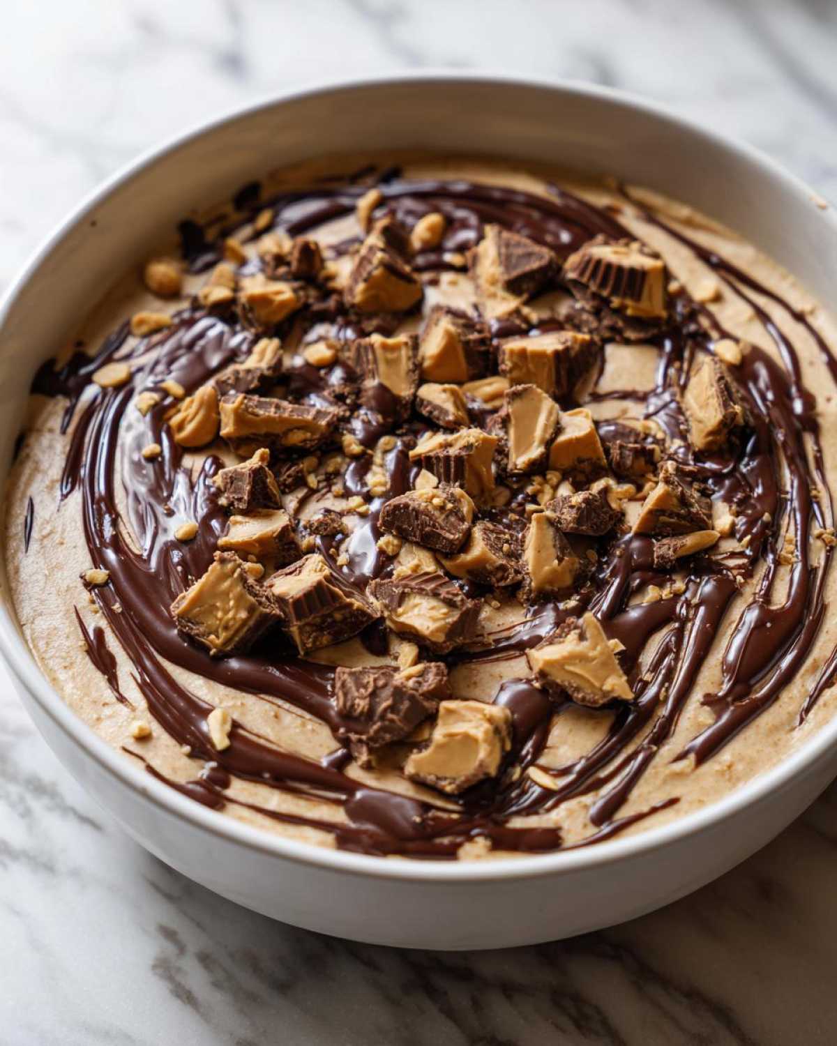 Close-up of Chocolate Peanut Butter Cheesecake Dip topped with chocolate drizzle and chopped peanut butter cups.