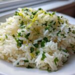 A mound of fluffy white Cilantro Lime Rice topped with chopped cilantro and bright yellow lime zest.