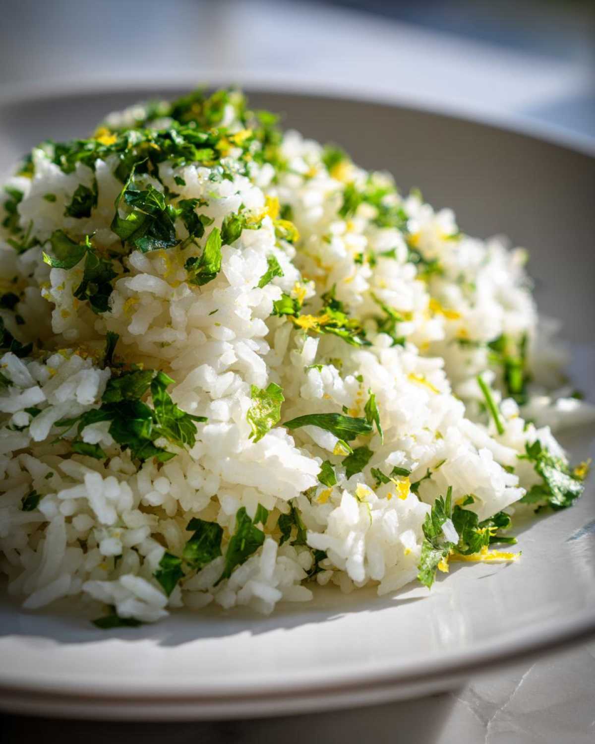 Close-up of fluffy white Cilantro Lime Rice topped with fresh chopped cilantro and bright yellow lime zest.