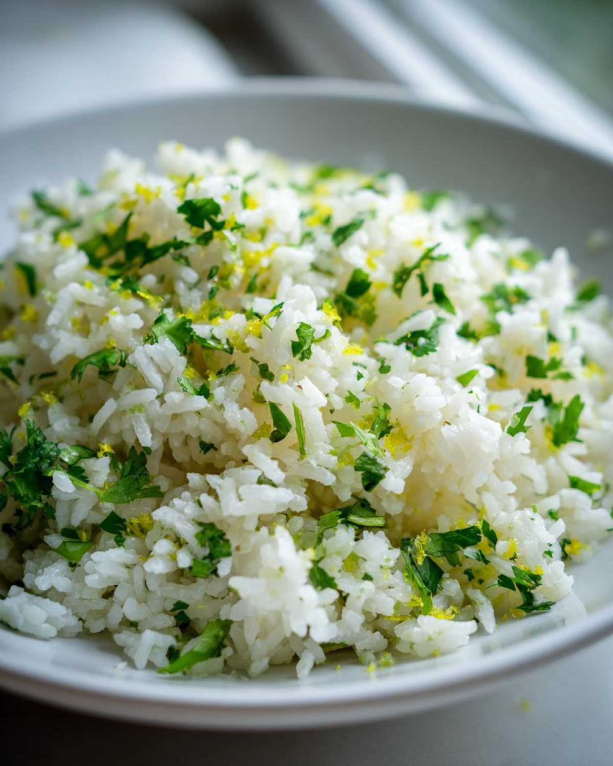 Close-up of fluffy Cilantro Lime Rice topped with chopped cilantro and bright yellow lime zest.