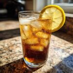 A tall glass filled with ice, dark liquid, and a lemon slice, representing Cold Brew Lemonade.