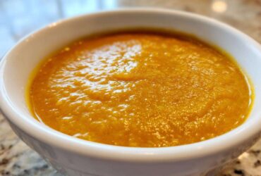 Close-up of a thick, vibrant orange Creamy Coconut Lentil Soup served in a white bowl.