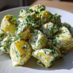 Close-up of bright yellow potatoes coated in a creamy dressing and fresh dill, showcasing the Creamy Dill Potato Salad.