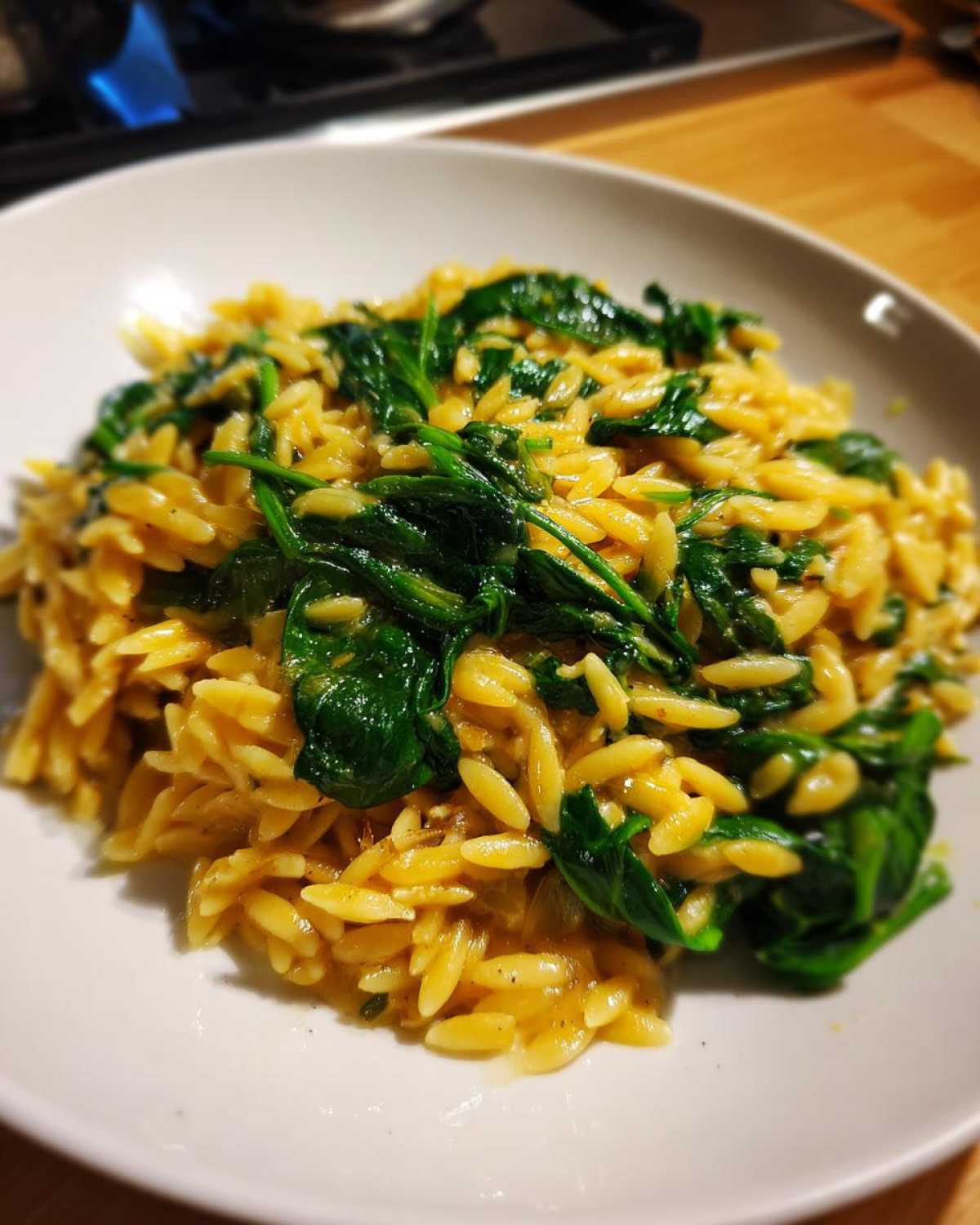 Close-up of a white bowl filled with creamy Garlic Parmesan Orzo with Spinach.