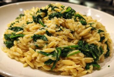 A close-up of a bowl of Creamy Garlic Parmesan Orzo with Spinach, topped with grated cheese.