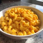 A close-up of creamy, bright orange Instant Pot Mac and Cheese served in a white bowl.
