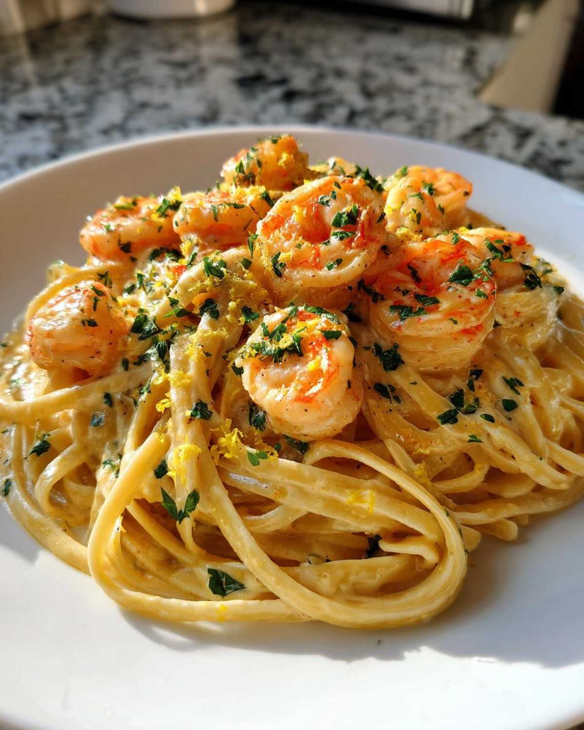 Close-up of Creamy Lemon Garlic Shrimp Pasta topped with shrimp, parsley, and lemon zest.