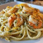 Close-up of a serving of Creamy Lemon Garlic Shrimp Pasta topped with bright shrimp and lemon zest.