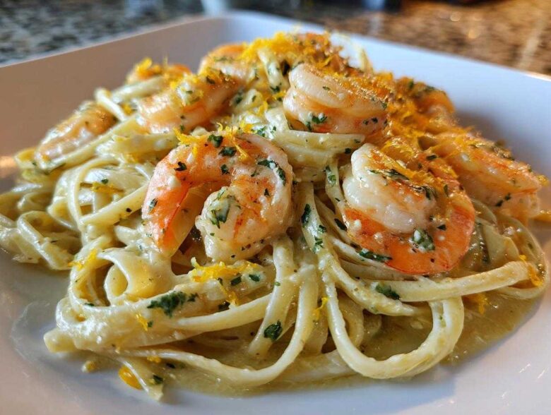 Close-up of a serving of Creamy Lemon Garlic Shrimp Pasta topped with bright shrimp and lemon zest.