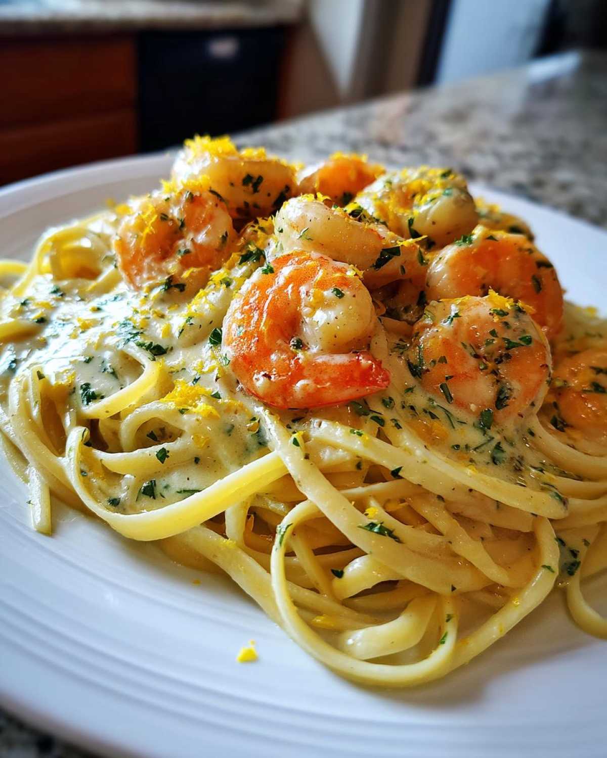 Close-up of a plate piled high with Creamy Lemon Garlic Shrimp Pasta, topped with plump shrimp and lemon zest.