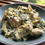 Close-up of a bowl filled with rich Creamy Spinach Artichoke Chicken Skillet.