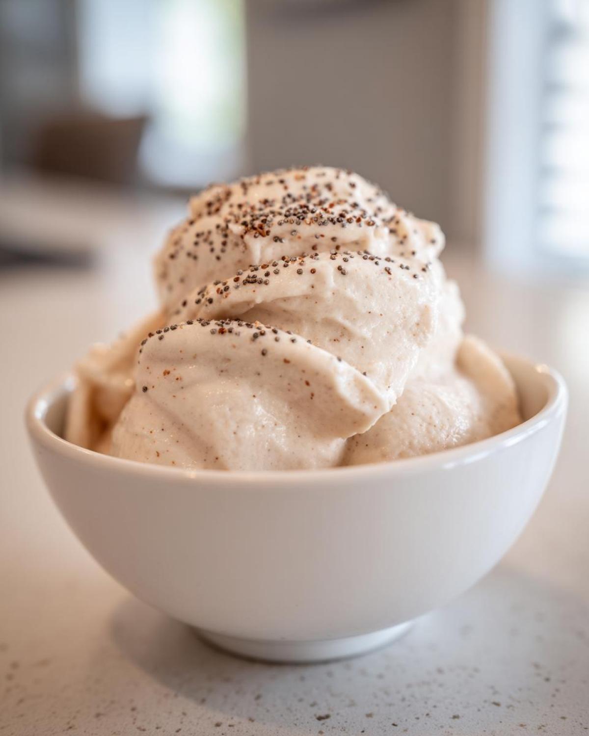 A thick, creamy vanilla protein smoothie bowl served in a white bowl and topped with small dark seeds.