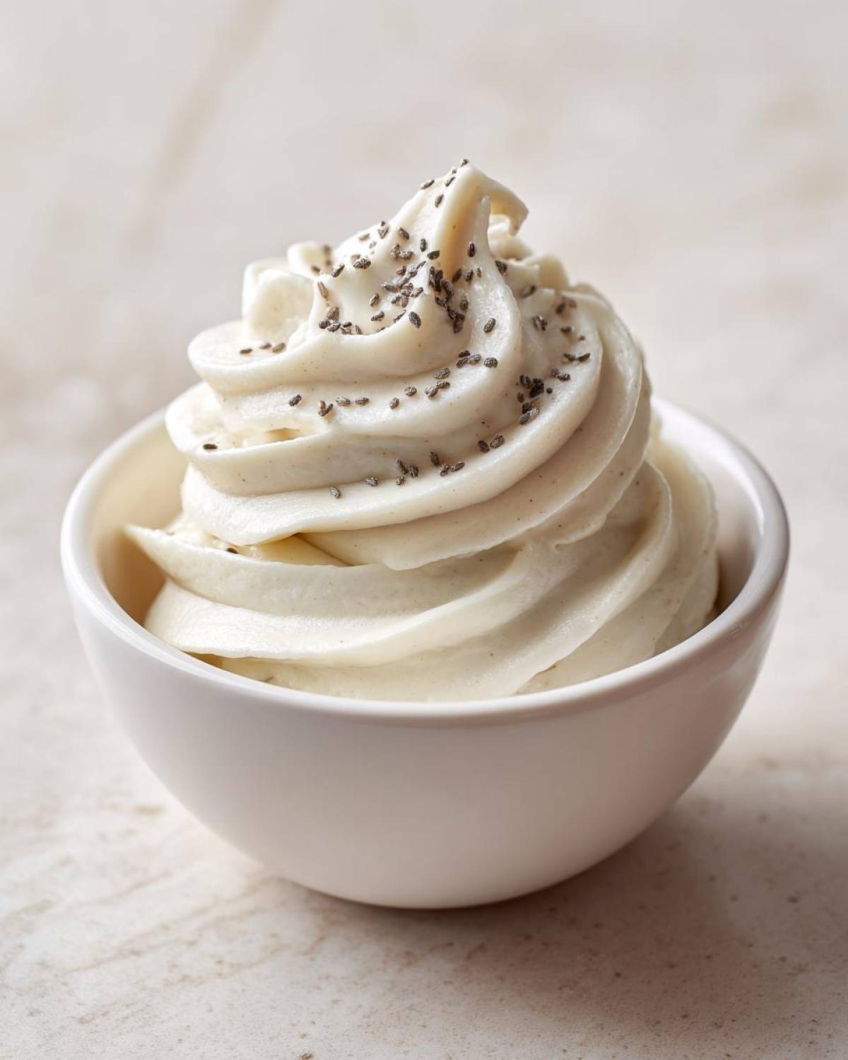 A close-up of a perfectly swirled Creamy Vanilla Protein Smoothie Bowl topped with dark chia seeds.
