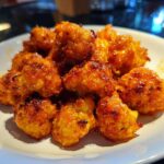 Close-up of glossy, orange-glazed Crispy Air Fryer Cauliflower Wings piled on a white plate.