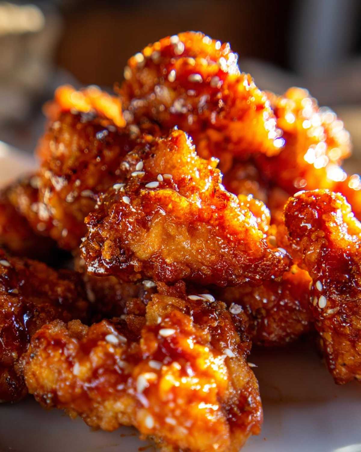 Close-up of saucy, golden Crispy Air Fryer Cauliflower Wings sprinkled with white sesame seeds.
