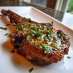 Close-up of a perfectly cooked Crispy Air Fryer Pork Chop topped with glistening garlic butter and fresh parsley.
