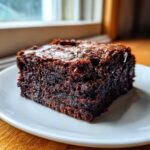 A close-up of a rich, fudgy Dark Chocolate Tahini Brownies square on a white plate.