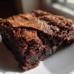 Close-up of a single, fudgy Dark Chocolate Tahini Brownies square with a crackly top sprinkled with sea salt.
