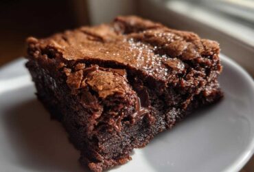 Close-up of a single, fudgy Dark Chocolate Tahini Brownies square with a crackly top sprinkled with sea salt.