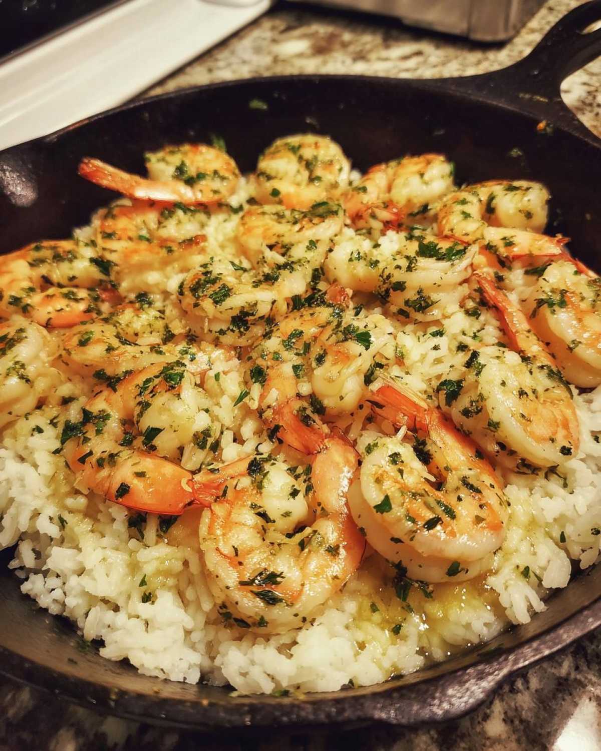 A close-up of Garlic Butter Shrimp and Rice Skillet served in a cast iron pan, topped with parsley.