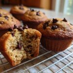 Close-up of moist Gluten-Free Banana Chocolate Chip Muffins cooling on a wire rack, one muffin is broken open.