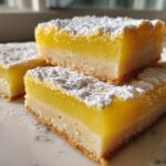 Close-up of stacked Gluten-Free Lemon Bars with shortbread crust, dusted heavily with powdered sugar.