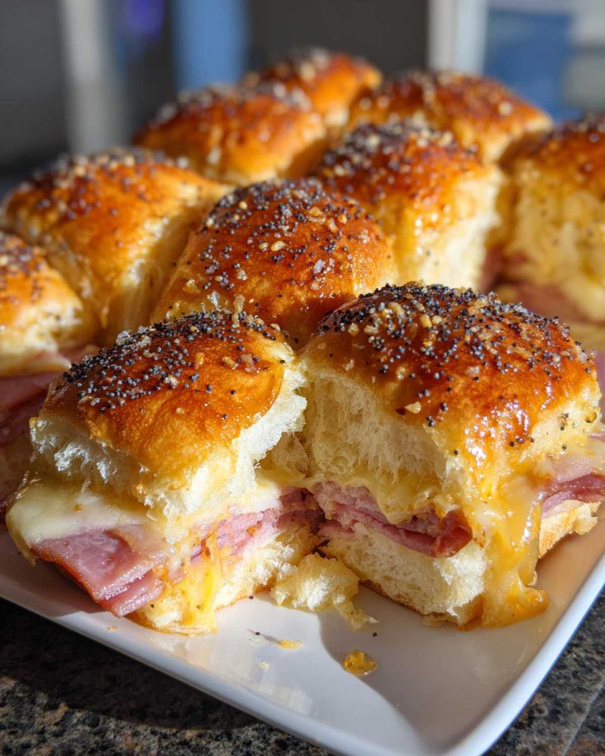 Close-up of Hawaiian Roll Ham and Cheese Sliders, showing melted cheese and poppy seed topping.