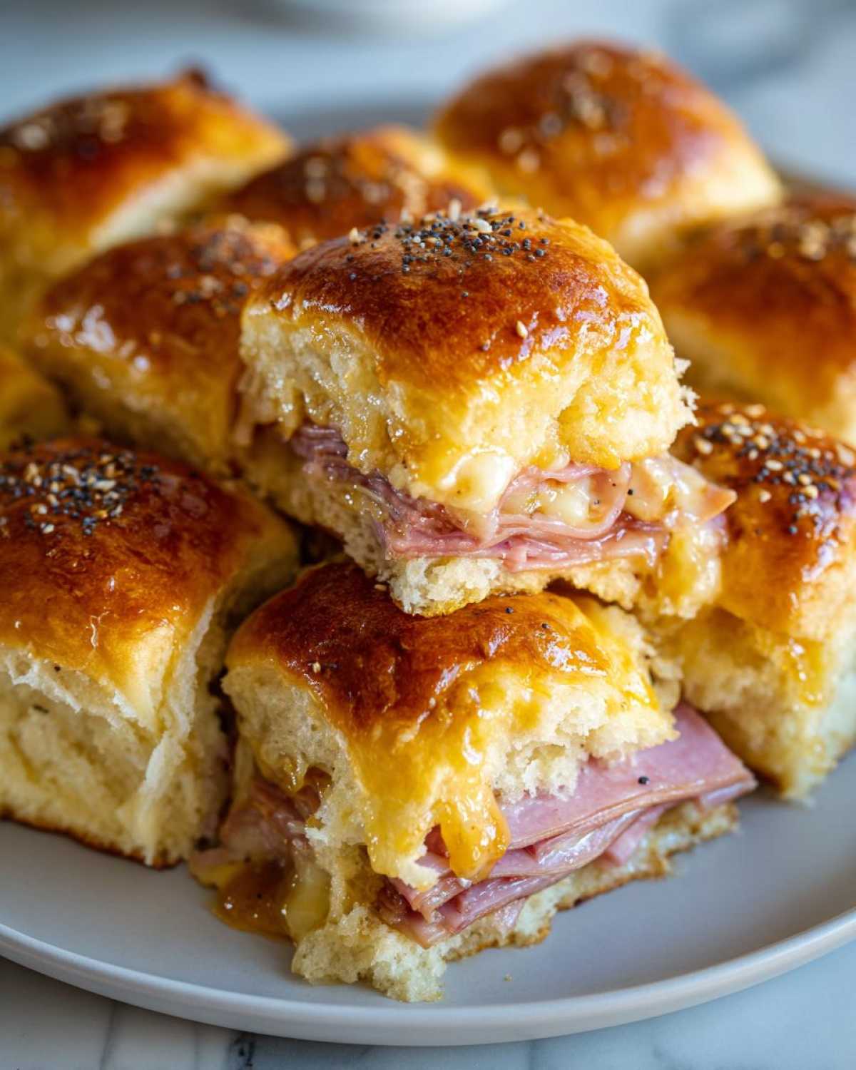 Close-up of baked Hawaiian Roll Ham and Cheese Sliders with melted cheese and poppy seed topping.