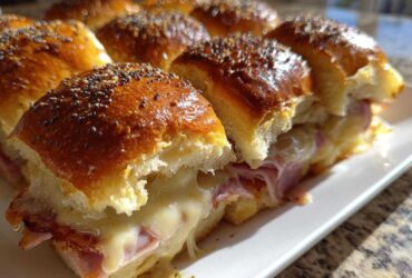 Close-up of gooey Hawaiian Roll Ham and Cheese Sliders with melted Swiss cheese and poppy seeds on top.