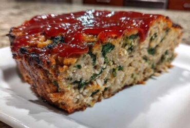 A thick slice of Healthy Turkey Spinach Meatloaf topped with a glossy ketchup glaze, showing visible spinach pieces.