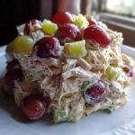 A mound of creamy Honey Mustard Chicken Salad with Grapes and celery served on a white plate.