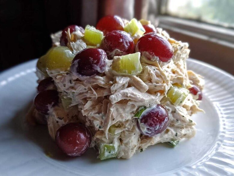 A mound of creamy Honey Mustard Chicken Salad with Grapes and celery served on a white plate.