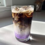 A refreshing Iced Lavender Latte showing distinct purple syrup, milk, and espresso layers over ice.