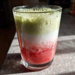 A vibrant, layered Iced Strawberry Matcha Latte showing red strawberry puree, white milk, and green matcha foam.