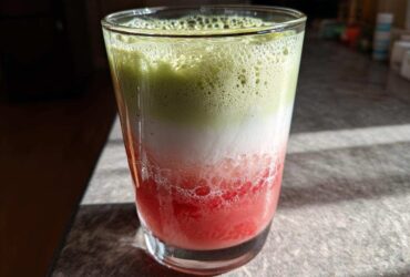 A vibrant, layered Iced Strawberry Matcha Latte showing red strawberry puree, white milk, and green matcha foam.