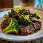 Close-up of tender slices of Instant Pot Beef and Broccoli coated in a rich brown sauce, garnished with parsley.