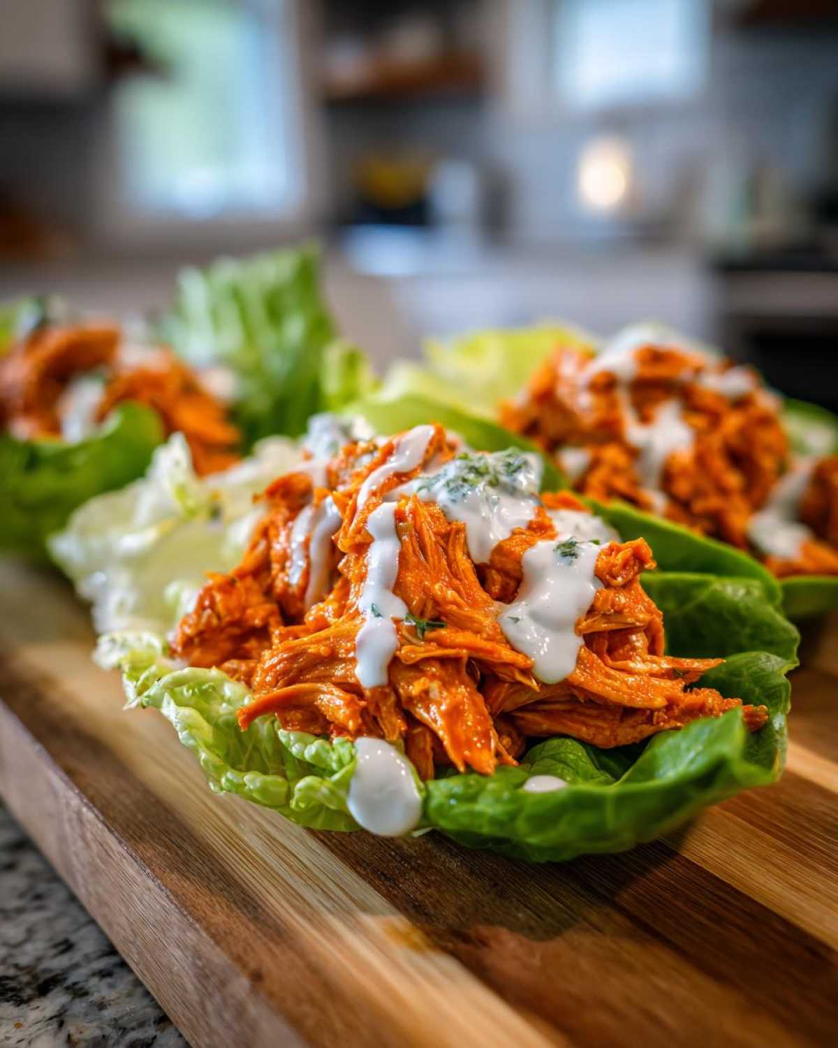 Close-up of Keto Buffalo Chicken Lettuce Wraps filled with shredded orange buffalo chicken and drizzled with ranch.