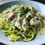 Close-up of Keto Chicken Alfredo served over bright green zucchini noodles, topped with creamy sauce and parsley.