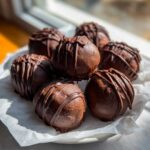 A pile of rich, chocolate-covered Keto Chocolate Peanut Butter Fat Bombs drizzled with extra chocolate.