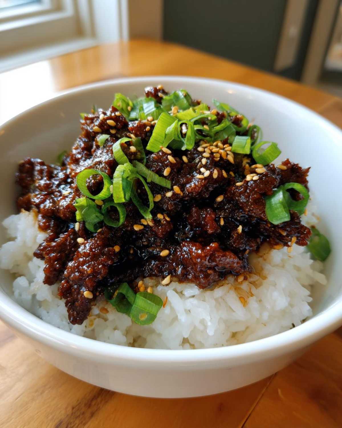 Close-up of Korean Ground Beef Bulgogi Bowls featuring savory ground beef over white rice, topped with green onions and sesame seeds.
