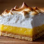 A close-up of one perfect Lemon Meringue Pie Bars showing the crust, bright lemon filling, and toasted meringue topping.