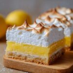 Close-up of a thick slice of Lemon Meringue Pie Bars showing crust, bright yellow lemon filling, and fluffy, toasted meringue.