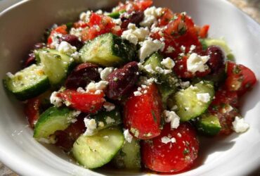 A vibrant close-up of Mediterranean Cucumber Tomato Salad featuring chunks of cucumber, tomato, Kalamata olives, and crumbled feta cheese.