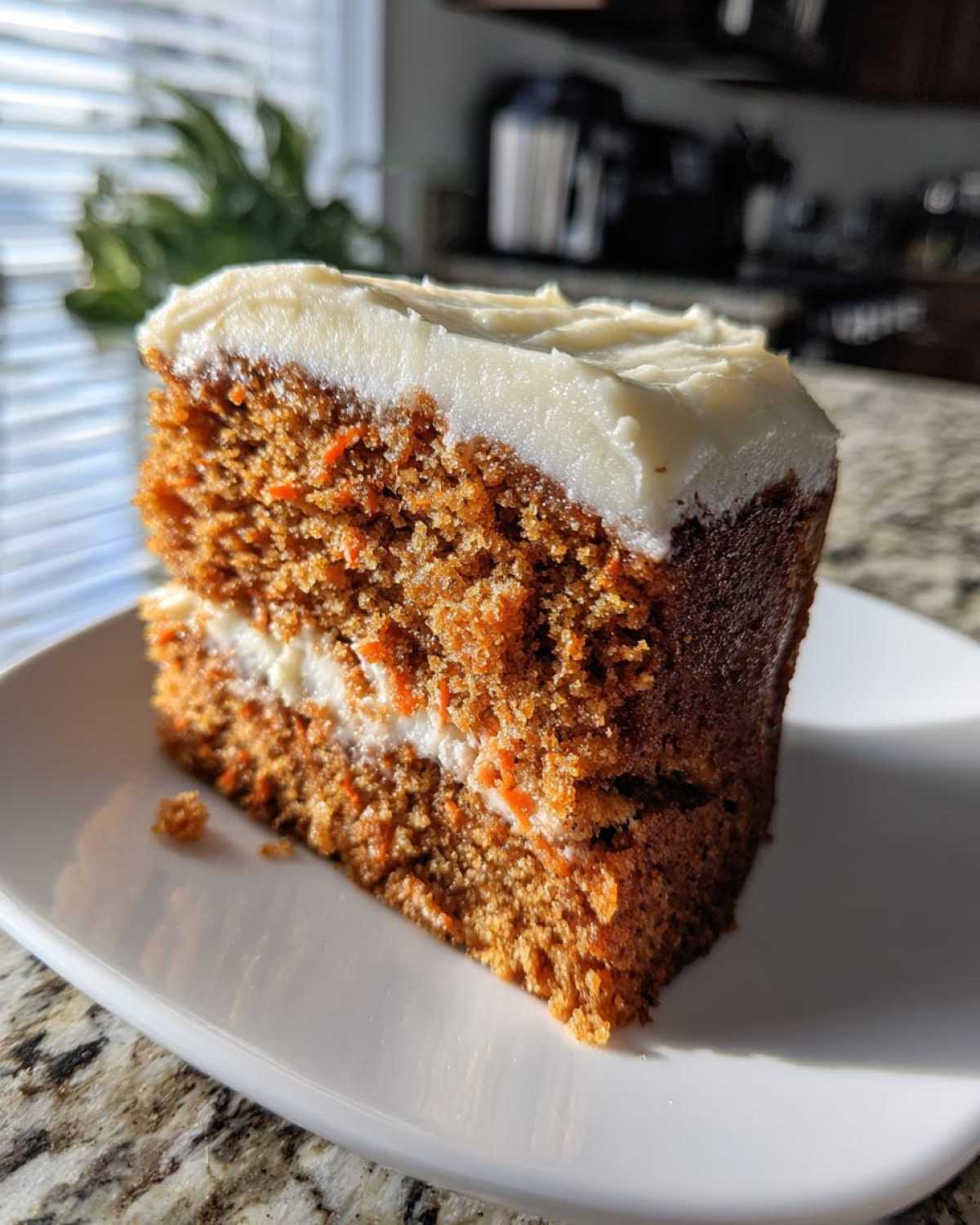 Close-up of a thick slice of Moist Carrot Cake with Cream Cheese Frosting, showing its texture.