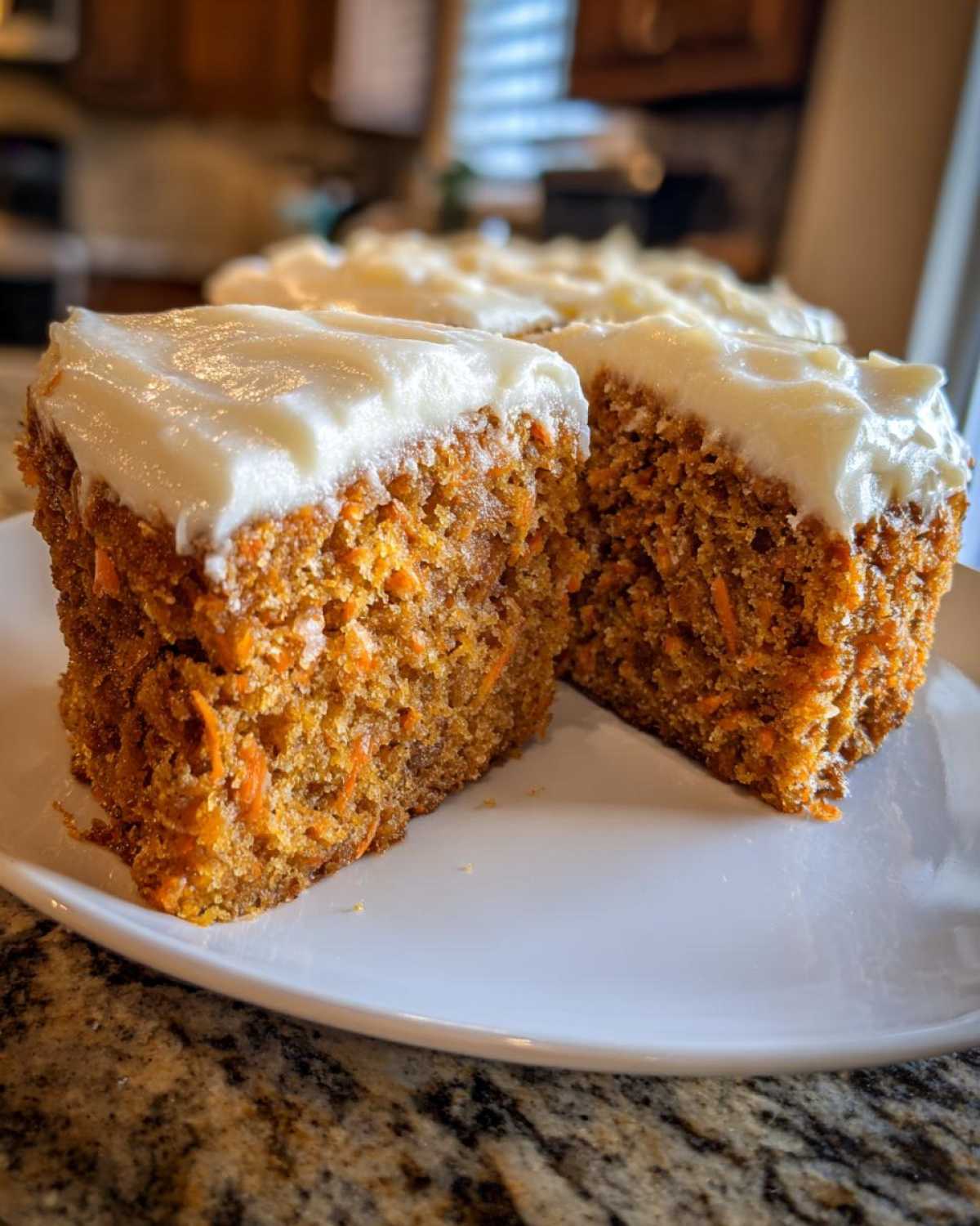 Two thick slices of Moist Carrot Cake with Cream Cheese Frosting on a white plate.
