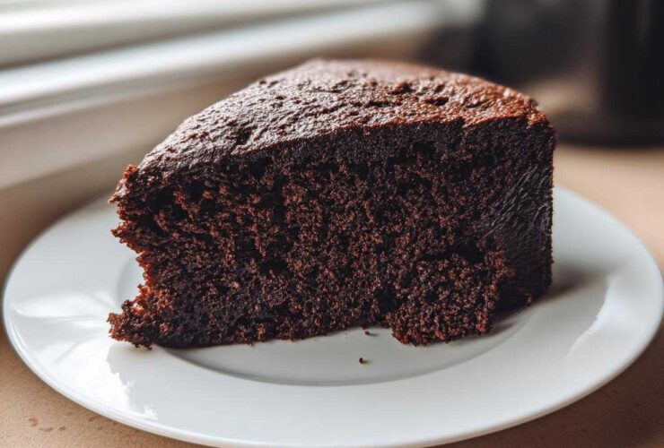 Close-up of a rich, dark slice of Gluten-Free Chocolate Cake on a white plate.